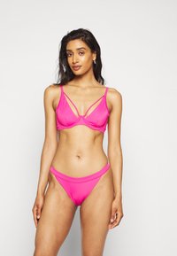 Conjunto de biquíni rosa com um top triângulo e detalhes nas alças, acompanhado de cuecas de cintura alta, feito de um tecido macio e elástico.