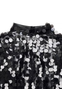 Mustakankainen verkko kangas, jossa on suuria, vuorottelevia mustia ja valkoisia paljetteja, luoden kiiltävän, tekstuuripinnan. Korkea kaulus ja takana suljenta.