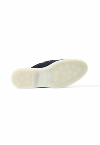 Granatowe zamszowe buty slip-on z białą gumową podeszwą, wyposażoną w okrągłe wzory trakcyjne oraz wytłoczone logo na pięcie.