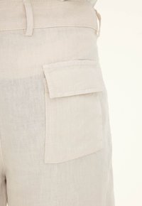 Light beige linen shorts with a textured finish, featuring a side pocket and stitched accents for added detail.