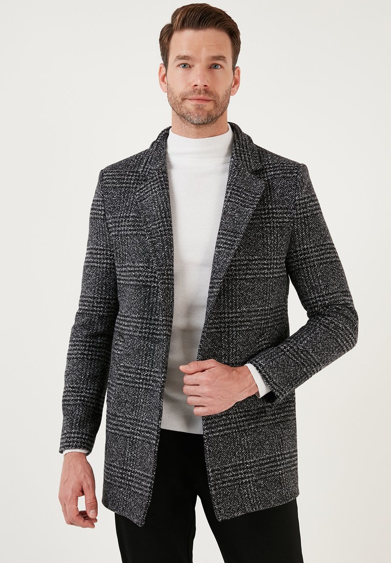 Abrigo de cuadros negro y blanco para hombre, hecho de un tejido texturizado, con cuello de muesca y diseño de un solo pecho, y dos bolsillos.