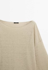 Pull en maille beige à manches longues avec un large col rond, présenté sur un fond blanc uni.