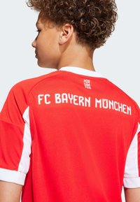 FC Bayern München-drakt i rød med hvite detaljer. Har rund hals, kort erm og trykt tekst på baksiden. Myk stoffkvalitet.