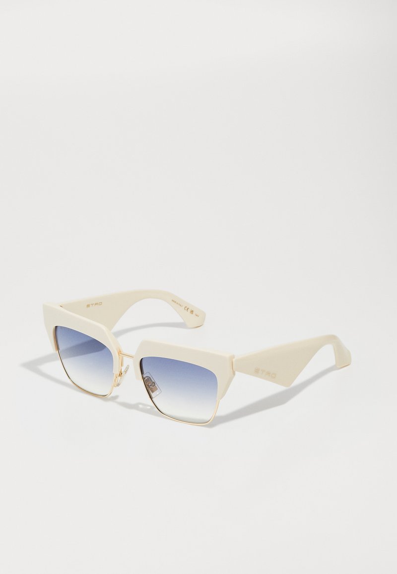 Óculos de sol angulares de cor creme com lentes azuis em degradê, apresentando detalhes em metal dourado e um acabamento texturizado nas hastes.
