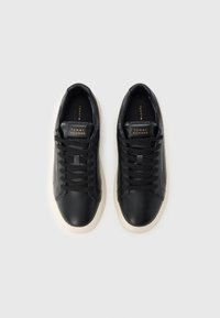 Mustadest nahast tossud lamedate paeltega, kontrastse valge kummist tallaga ja kaubamärgiga keeleosaga. Omavad sileda tekstuuriga ja minimalistlikku disaini.