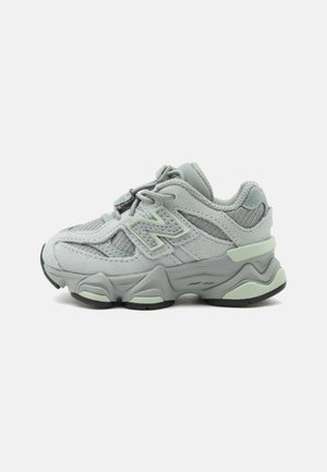 Baskets de sport gris clair et vert menthe avec des panneaux en mesh et en daim, semelle épaisse et détail du logo sur le côté, vues de côté gauche.