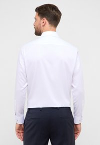 Witte blouse met lange mouwen, een klassieke kraag, een gladde textuur en geruite manchetten, gecombineerd met marineblauwe broek, met een op maat gemaakte pasvorm.