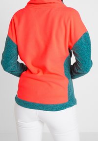 Sudadera de forro polar con alto cuello; presenta un cuerpo de un brillante coral y mangas de un azul oscuro; tejido texturizado con paneles de color contrastante.