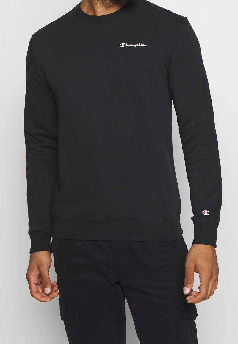 Sudadera negra de mezcla de algodón, con cuello redondo y puños de canalé. Pequeño logotipo blanco de "Champion" en el lado izquierdo del pecho; color sólido en todo el producto.