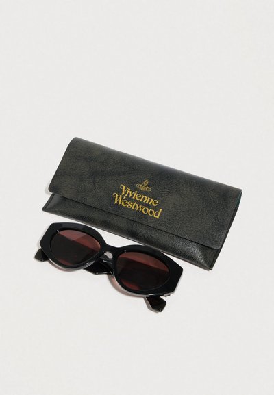 Μαύρες υπερμεγέθεις ηλιακές γυαλιά με φακούς κόκκινου τόνου, συνοδευόμενα από μία υφασμάτινη μαύρη θήκη με χρυσά διακριτικά "Vivienne Westwood".