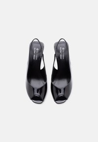 Γυναικεία πέδιλα slingback με ανοιχτά δάχτυλα από μαύρο πατεντέ δέρμα, με χαμηλό, χοντρό τακούνι, με την ετικέτα vegan και τη μάρκα Call It Spring.