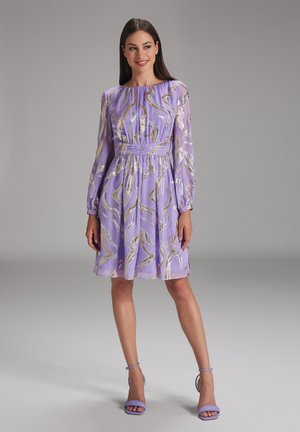 Lavender dress with long sleeves, gold swirled pattern, cinched waist, and flowing skirt. Paired with matching lavender heels.