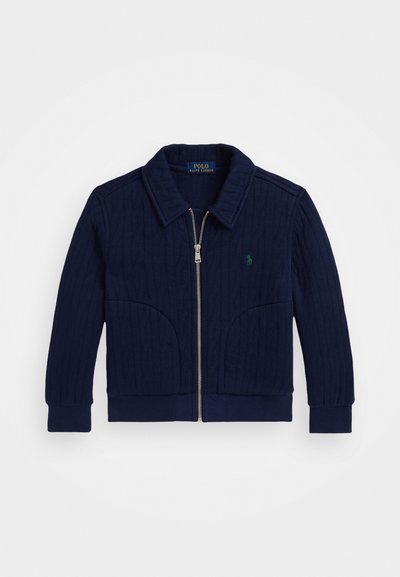 Casaco azul marinho com fecho éclair, apresentando um design em malha de corda texturizada, punhos e barra canelados, duas bolsos frontais e um pequeno logotipo bordado.