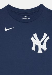 Mornarsko modra bombažna majica s krožnim izrezom, z belim logotipom Nike in perforirano grafiko New York Yankees na prsih.