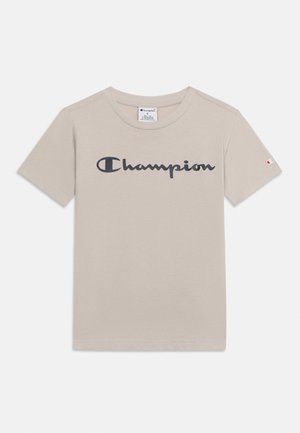 Hellbeiges T-Shirt mit kurzen Ärmeln und Rundhalsausschnitt, schwarzem "Champion"-Logo auf der Brust und kleinem Champion-Emblem am linken Ärmel.