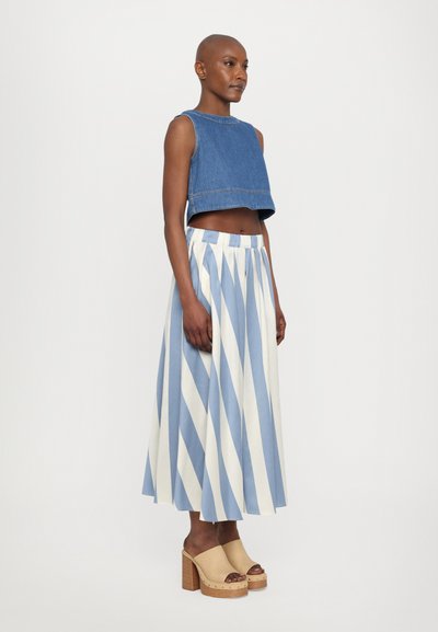 Denim crop top s okruglim izrezom. Naborana suknja u svijetloplavim i bijelim prugama. Tamne platforme s drvenom teksturom na potplatu.
