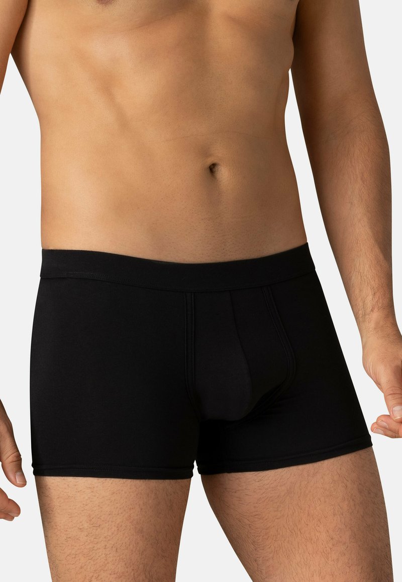 Boxers noirs ajustés en tissu extensible, avec une coupe serrée, une taille élastique et des détails de couture. Texture lisse, design classique.