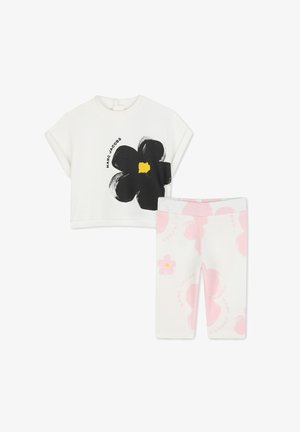 T-shirt bianco corto con design di fiori neri e centro giallo; leggings rosa a motivi con accenti floreali e logo del marchio.