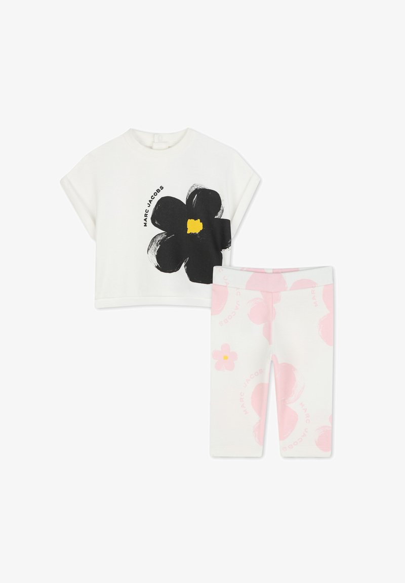 Witte cropped T-shirt met zwart bloemenontwerp en gele midden; rozenkleurige leggings met bloemenaccenten en merklogo.