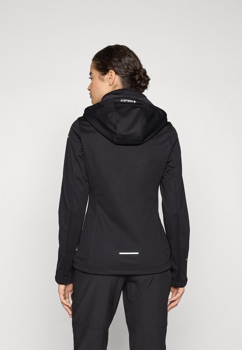 Chaqueta impermeable negra con un diseño ajustado, capucha ajustable y detalles reflectantes en la parte posterior. Fabricada con un tejido suave y elástico.