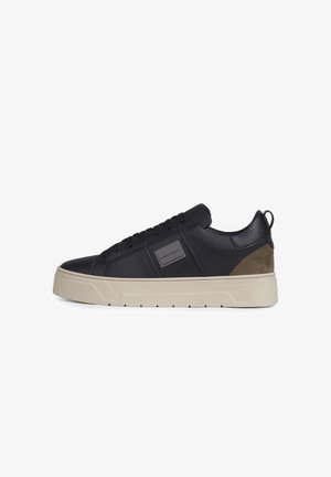 Zapatilla negra de caña baja con suela gruesa beige, diseño con cordones, parche texturizado en el talón y logotipo cuadrado de la marca en el panel lateral.