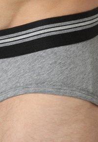 Graue Baumwollunterwäsche mit weicher Textur hat einen schwarzen Bund mit zwei grauen Streifen entlang der oberen Kante. Nähte sind sichtbar.