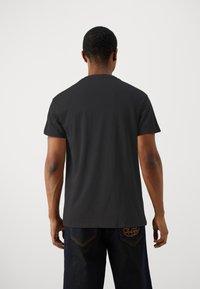 Tricou din bumbac negru, cu gât rotund și mâneci scurte, având o textură netedă și un design simplu, clasic.