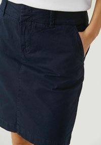 Námořnická modrá bavlněná tužková sukně s boční kapsou a hladkou strukturou, s čistým zakončením a minimalistickým designem.