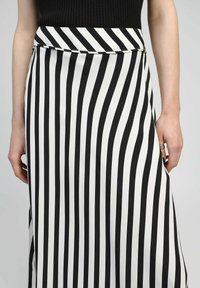 Jupe rayée noire et blanche en tissu lisse. Présente une taille élastique et des rayures verticales de largeur variable.