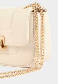 Borsa a tracolla in pelle sintetica color crema con una catenella dorata e un clasp in metallo dorato. Superficie testurizzata e forma rettangolare.