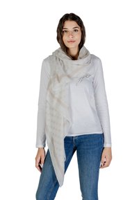 Sciarpa beige chiaro con una texture a motivo e dettaglio del logo, appoggiata sulle spalle, indossata sopra una camicia bianca a maniche lunghe e jeans blu.