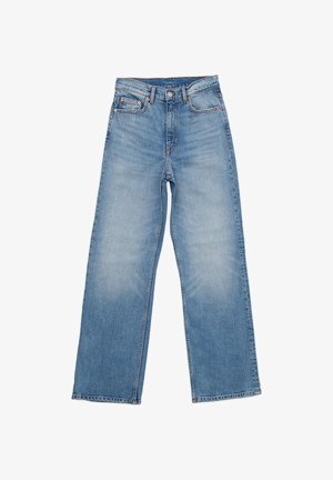 Jasnoniebieskie dżinsy mają prostą nogawkę, pięciokieszeniowy krój i guzikowy zamek. Tkanina ma lekko wypłowiały wygląd.