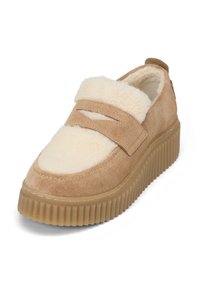 Beige Wildlederschuh mit einem flauschigen Schaffell-Obermaterial, verstellbarem Riemen vorne und gerillter Gummisohle für zusätzlichen Halt.