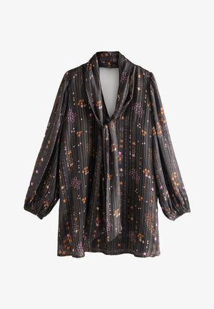 Sort transparent bluse med lange pufærmer, lodrette pudsestreger, en bundet V-hals og pink og orange stjernemønstre.