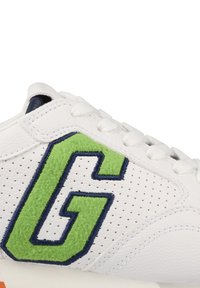 Białe sneakersy z perforowaną cholewką skórzaną, zieloną i granatową haftowaną literą "G" oraz białymi sznurowadłami. Teksturowane akcenty po bokach.
