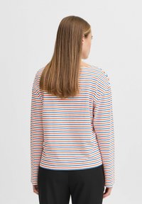 Chemise à manches longues rayée avec des rayures horizontales rouges, bleues et blanches. Tissu doux, coupe décontractée, col rond et couture arrière subtile.