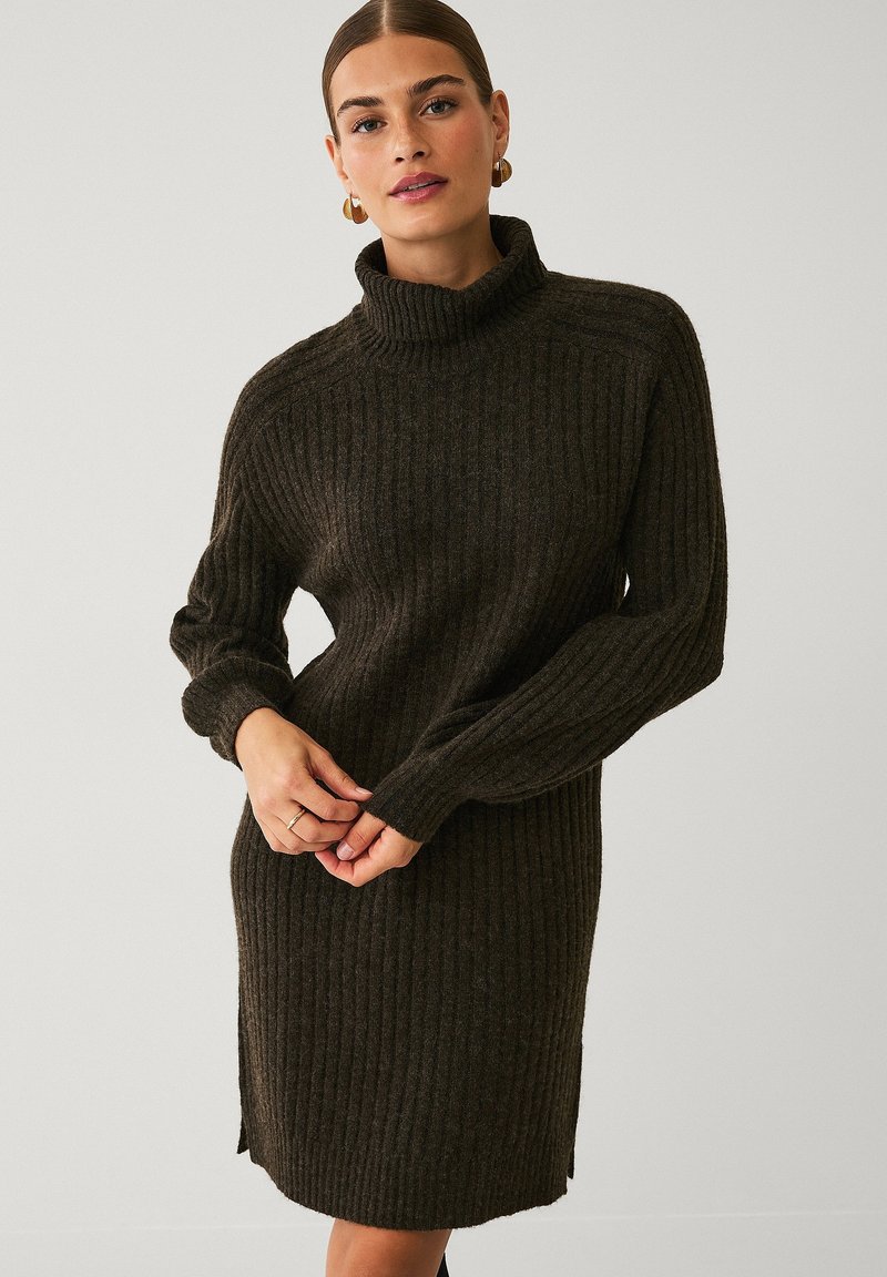 Braunes, geripptes Turtleneck-Kleid mit langen Ärmeln. Verfügt über seitliche Schlitze und eine lockere Passform. Der Stoff wirkt weich und strukturiert.