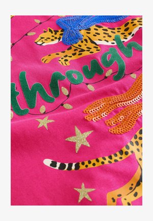 Pink fabric featuring green text "through," leopard prints, gold stars, and decorative sequins in blue and orange. Rich texture and vibrant design elements.