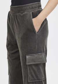 Grijze, zachte stoffen broek met een elastische tailleband, zijzakken en een grote cargozak op de dij. Daarom een gladde textuur en een ontspannen pasvorm.