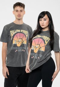 Gray cotton T-shirts featuring a colorful Rolling Stones graphic, including a tongue design and text. Loose fit, short sleeves.