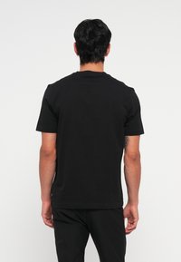 Camiseta negra de manga corta hecha de algodón, con escote redondo y diseño liso sin patrones ni logotipos visibles.