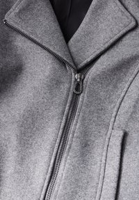 Manteau en mélange de laine gris avec un col à revers, fermeture éclair sur le devant et deux poches latérales, au toucher lisse.