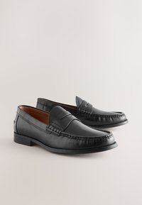 Mocassini in pelle nera con design da mocassino, caratterizzati da dettagli cuciti e tacco basso. Tessuto liscio con finitura lucida.