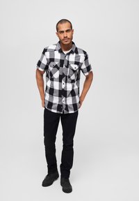 Korte mouwen geruit shirt in zwart-witte katoen stof; dit shirt heeft twee borstzakken, een knoop-sluiting aan de voorkant en een klassieke kraag.