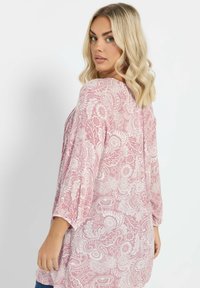 Pitkähihaista, vaaleanpunaista paitaa, jossa on valkoisia kukka- ja paisley-kuvioita. Pehmeä kangas, rento malli ja pyöreä kaula-aukko.