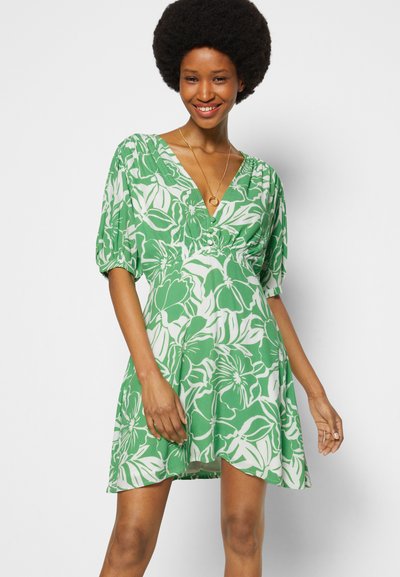 Vestido verde com padrão floral branco, decote em V, mangas curtas bufantes e um corte solto. Feito de tecido leve.
