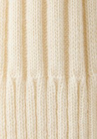Gros plan sur un tissu tricoté côtelé de couleur crème avec des lignes texturées verticales créant un motif tissé doux et épais.