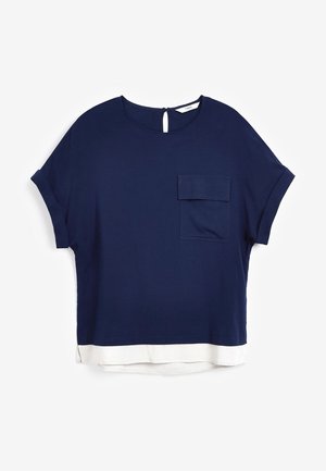 Top bleu marine à manches courtes avec col rond, poche frontale, ouverture dos boutonnée et détail de ourlet blanc superposé.