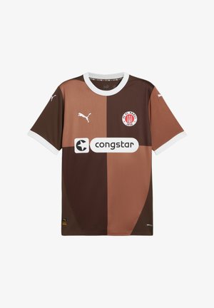 Smeđi nogometni dres s svjetlijim smešnim dijelovima, bijelim ovratnikom i kratkim rukavima. Ima Puma logo i logo sponzora na prednjoj strani.