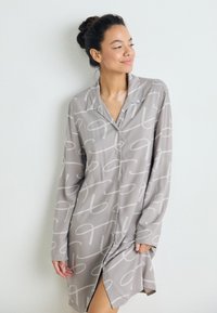 Siv nightdress z dolgimi rokavi z belim vrvnim vzorcem, gumbi na sprednji strani in stransko špranjo. Mehka tkanina, sproščen kroj, zasnova z ovratnikom.